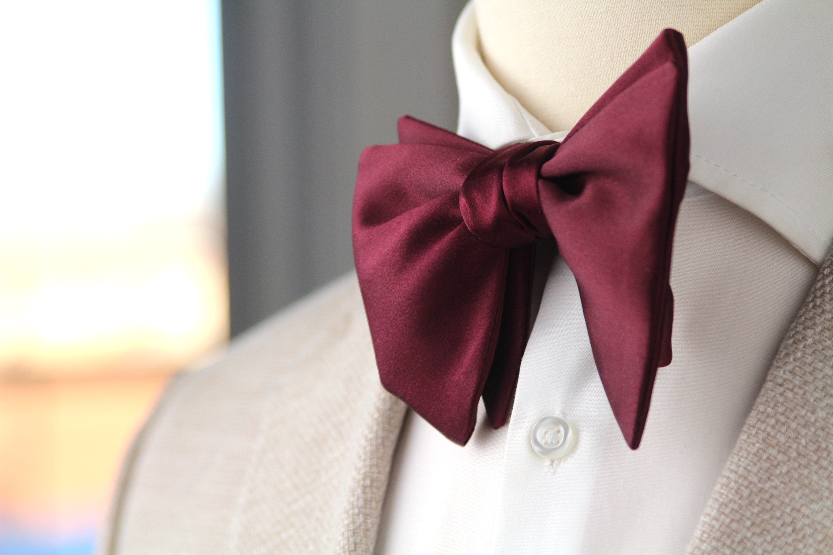 Maroon bow tie on a mannequin with a blurred background