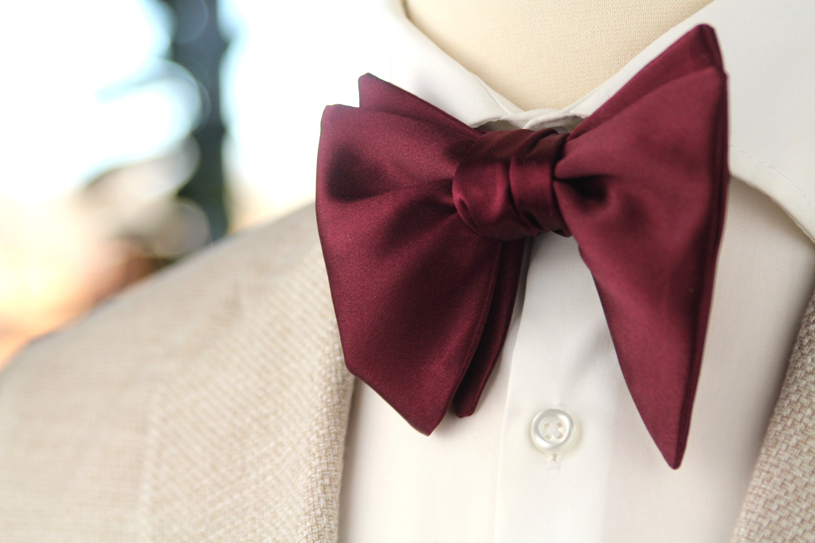 Maroon bow tie on a white shirt with a blurred background