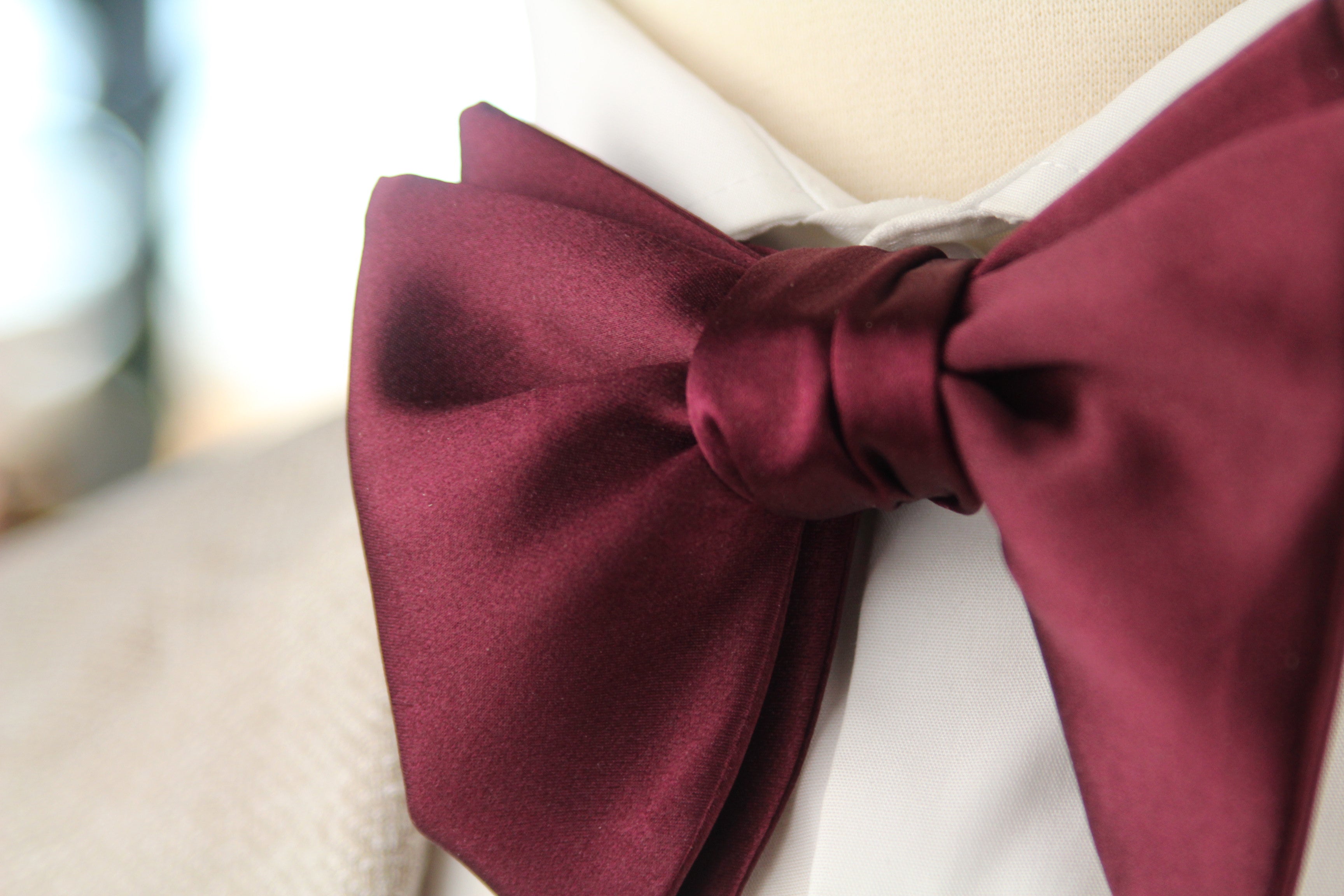 Maroon bow tie on a mannequin with a blurred background