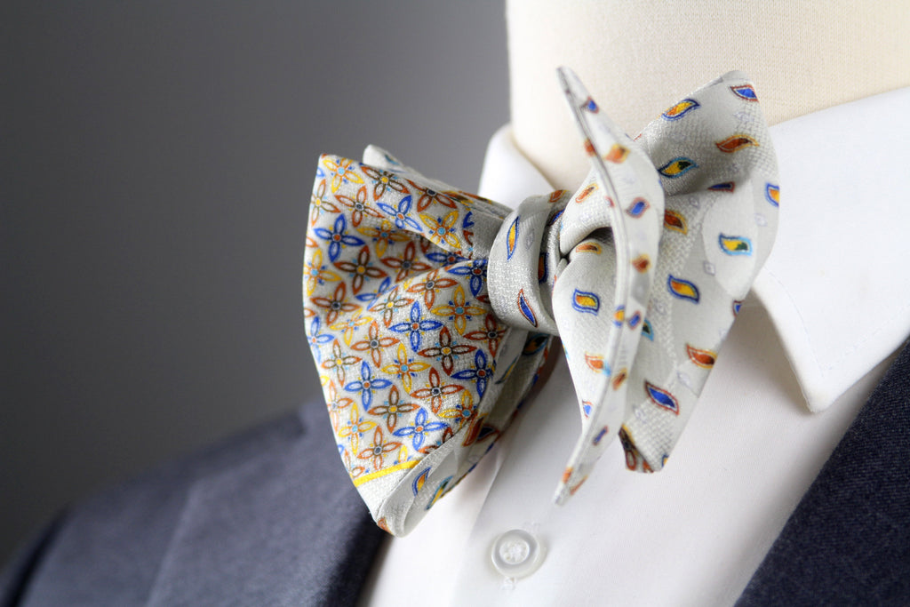 Two bow ties on a mannequin with a gray background