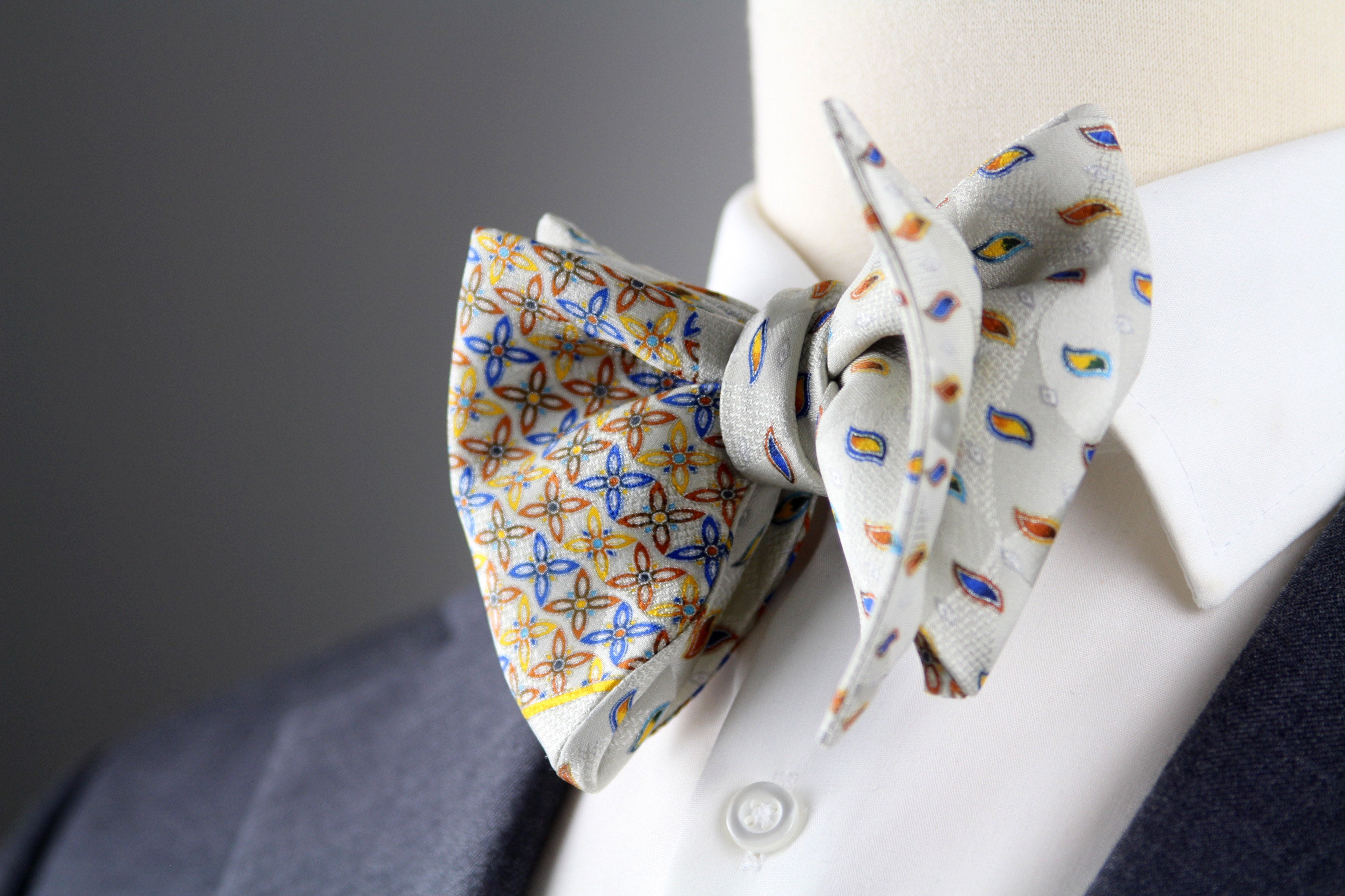 Two bow ties on a mannequin with a gray background