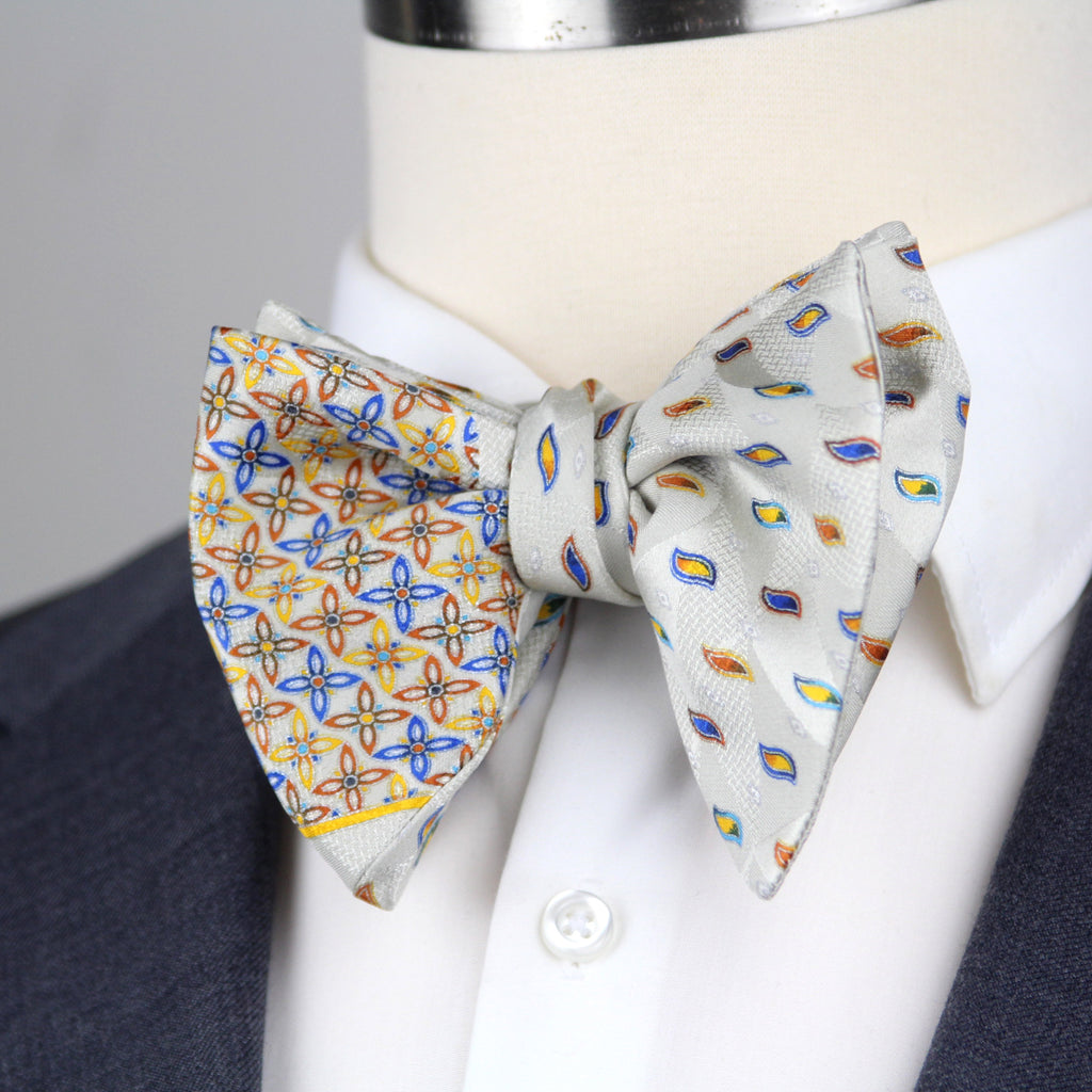 Two patterned bow ties on a mannequin with a gray background