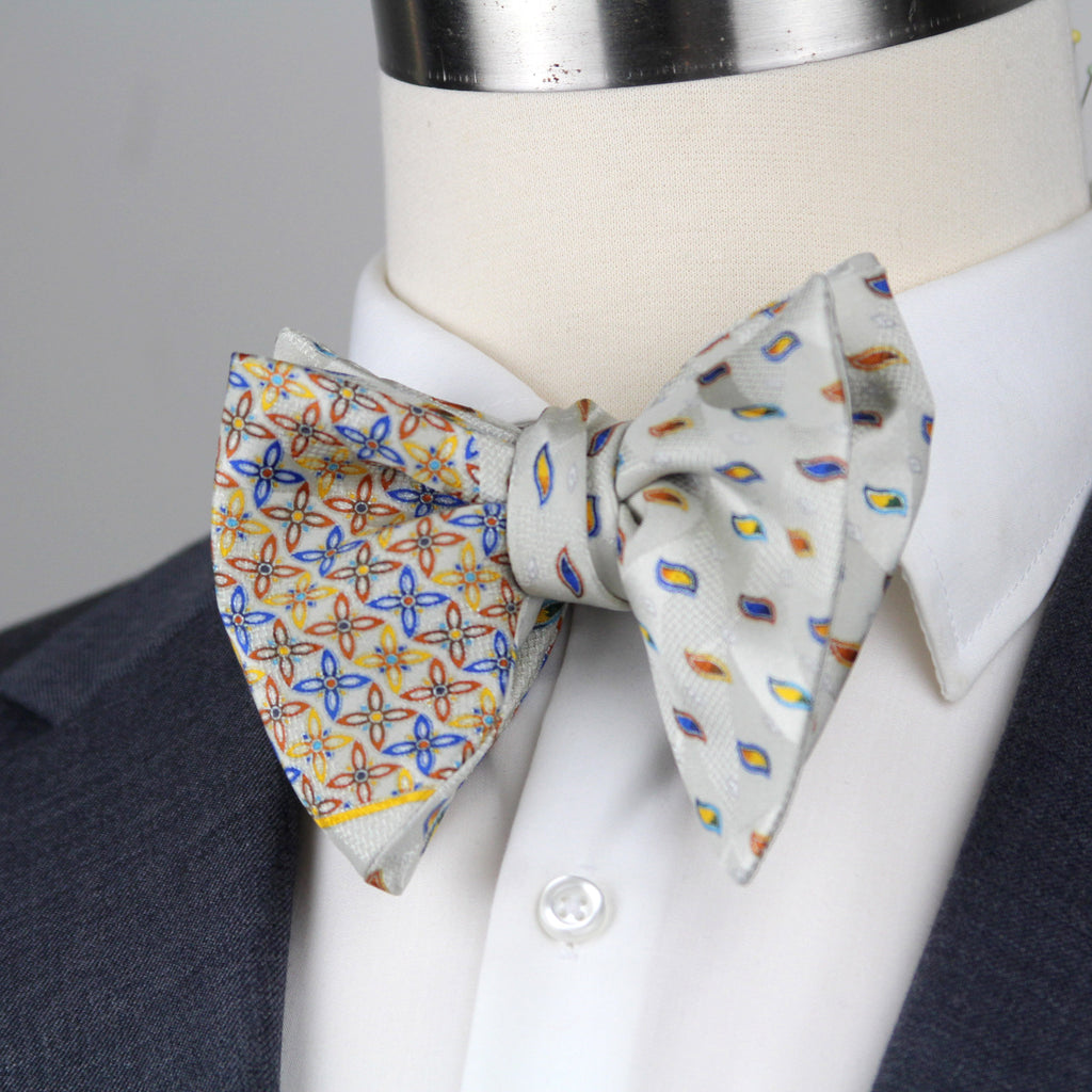 Two patterned bow ties on a mannequin with a suit jacket.