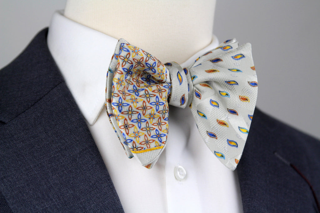 Two bow ties on a mannequin wearing a suit jacket against a gray background