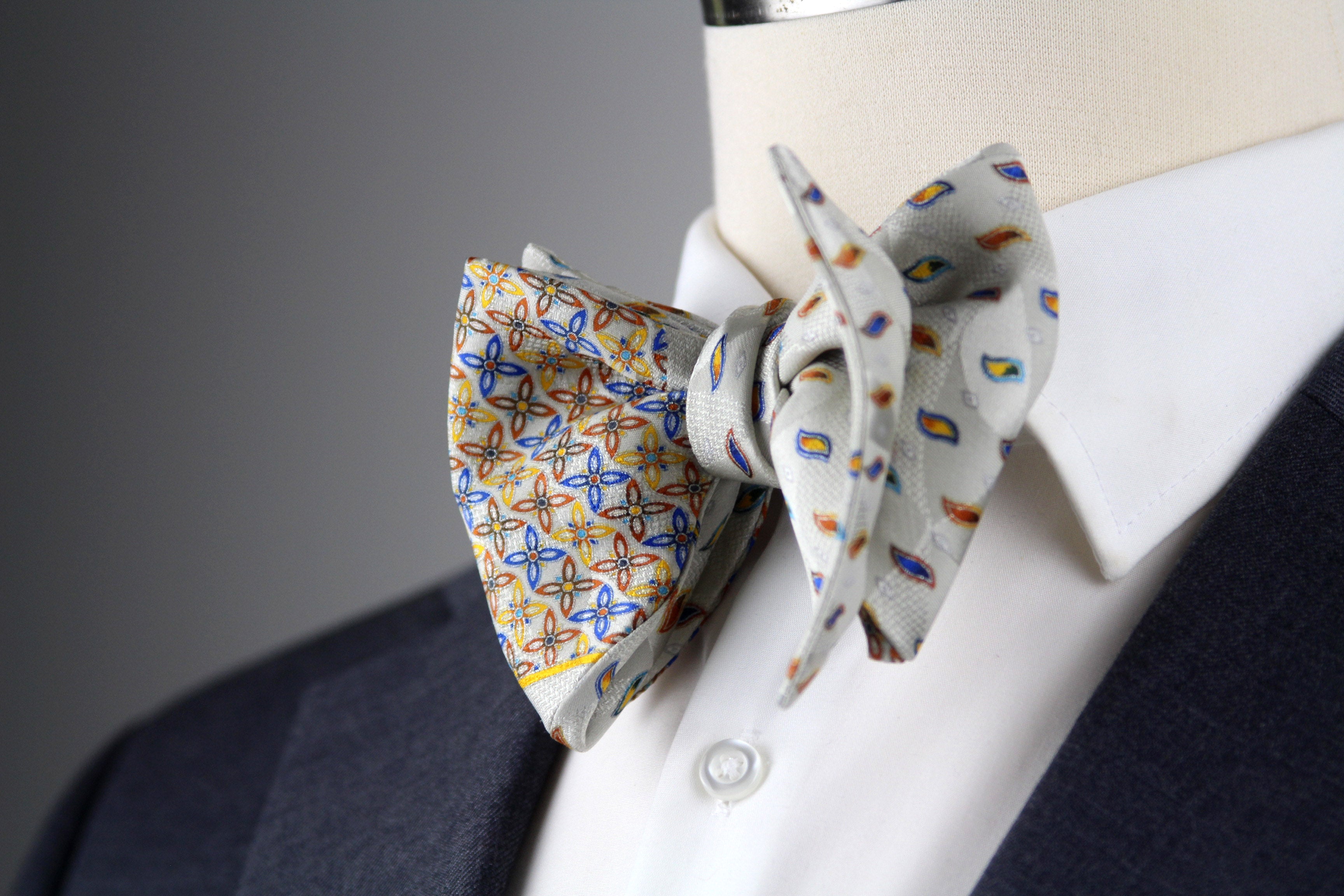 Two patterned bow ties on a mannequin with a suit jacket.