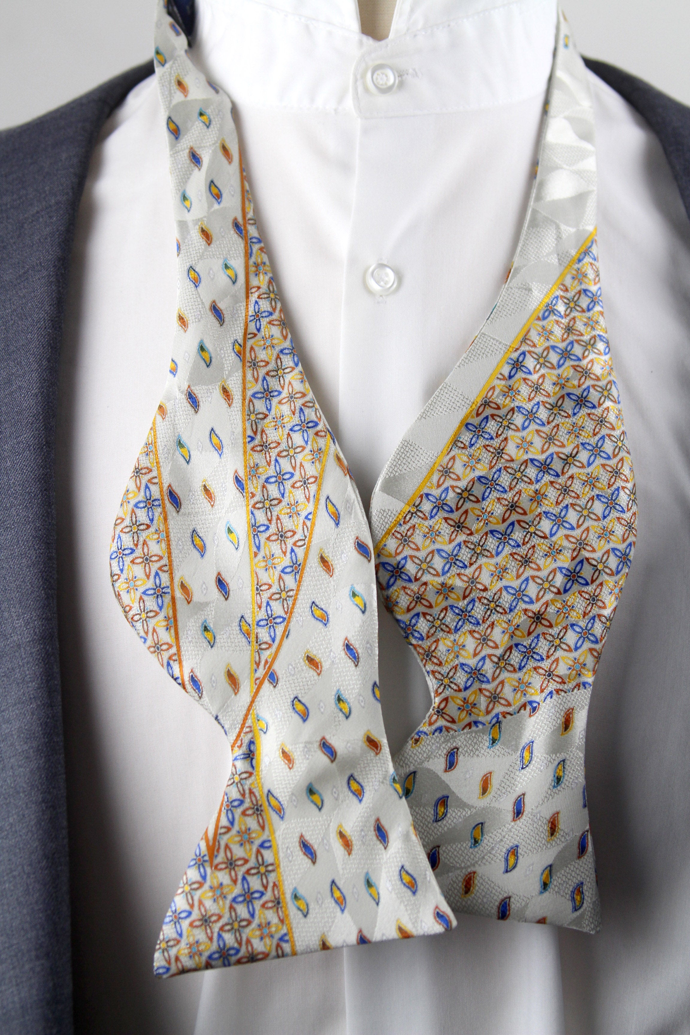 Colorful patterned bow tie on a white shirt with a gray background