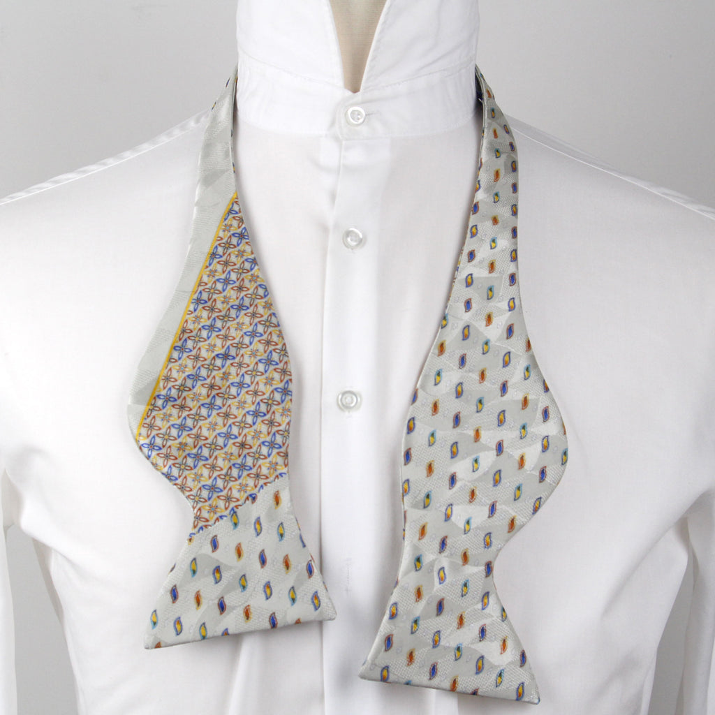 Patterned bow tie on a white shirt with a gray background