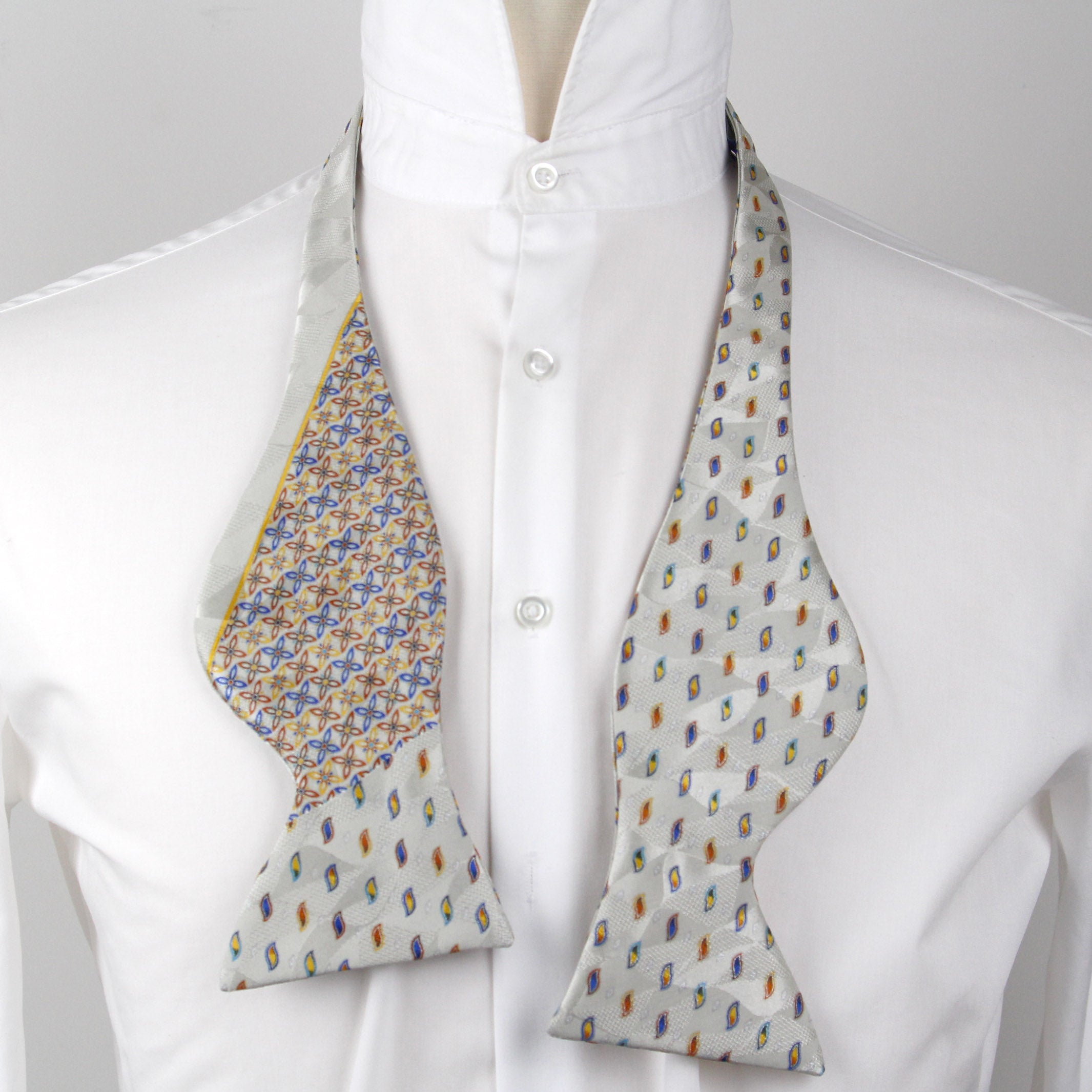 Patterned bow tie on a white shirt with a gray background