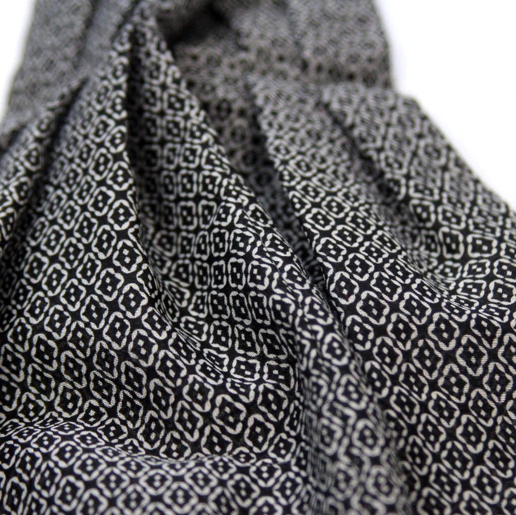 A close-up of draped fabric with a repeating black and off-white geometric block print pattern.