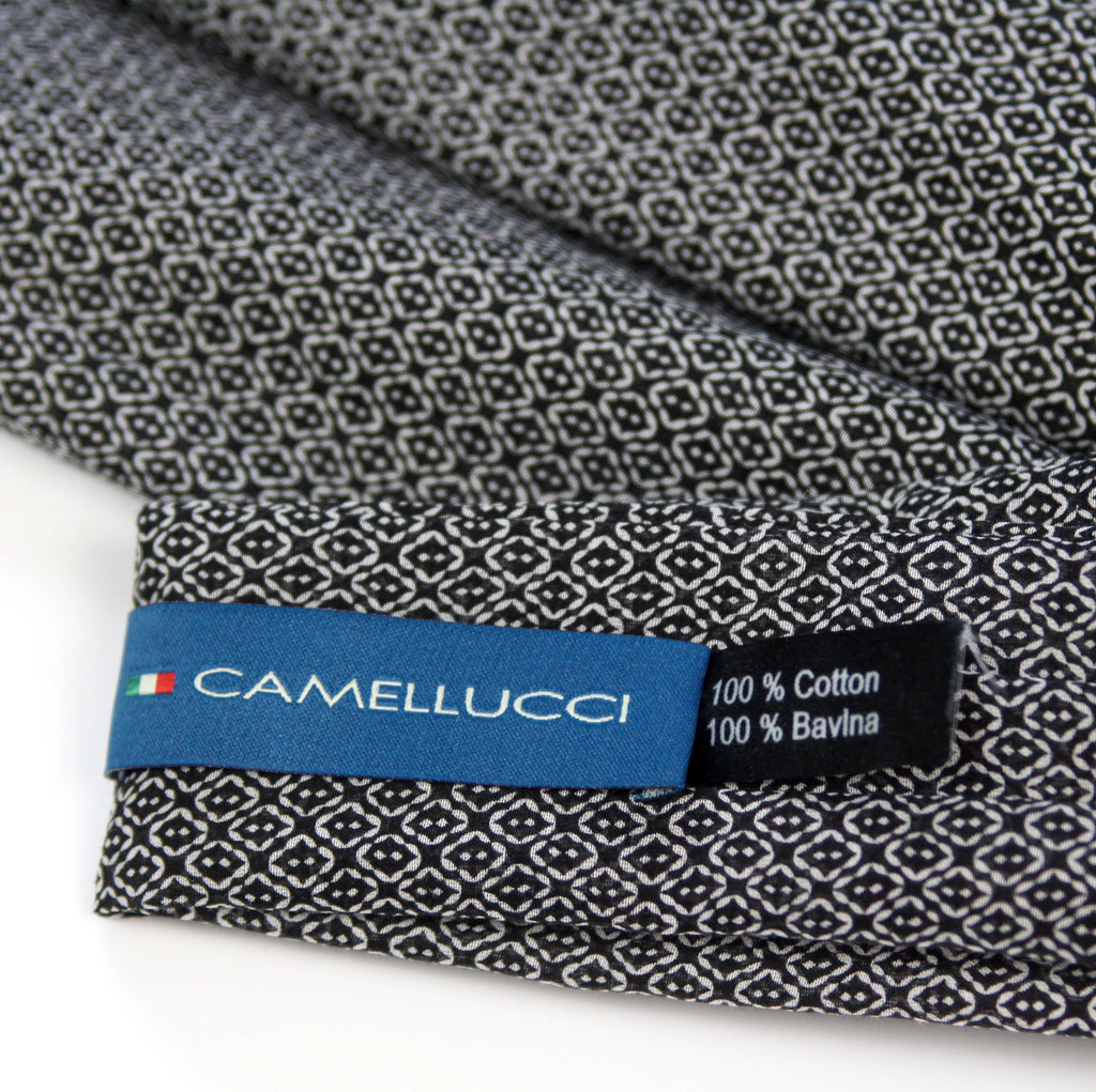 Close-up of a folded Camellucci cotton fabric with a black and white geometric pattern, showing a blue brand label and text reading 100% Cotton and 100% Bavlina.