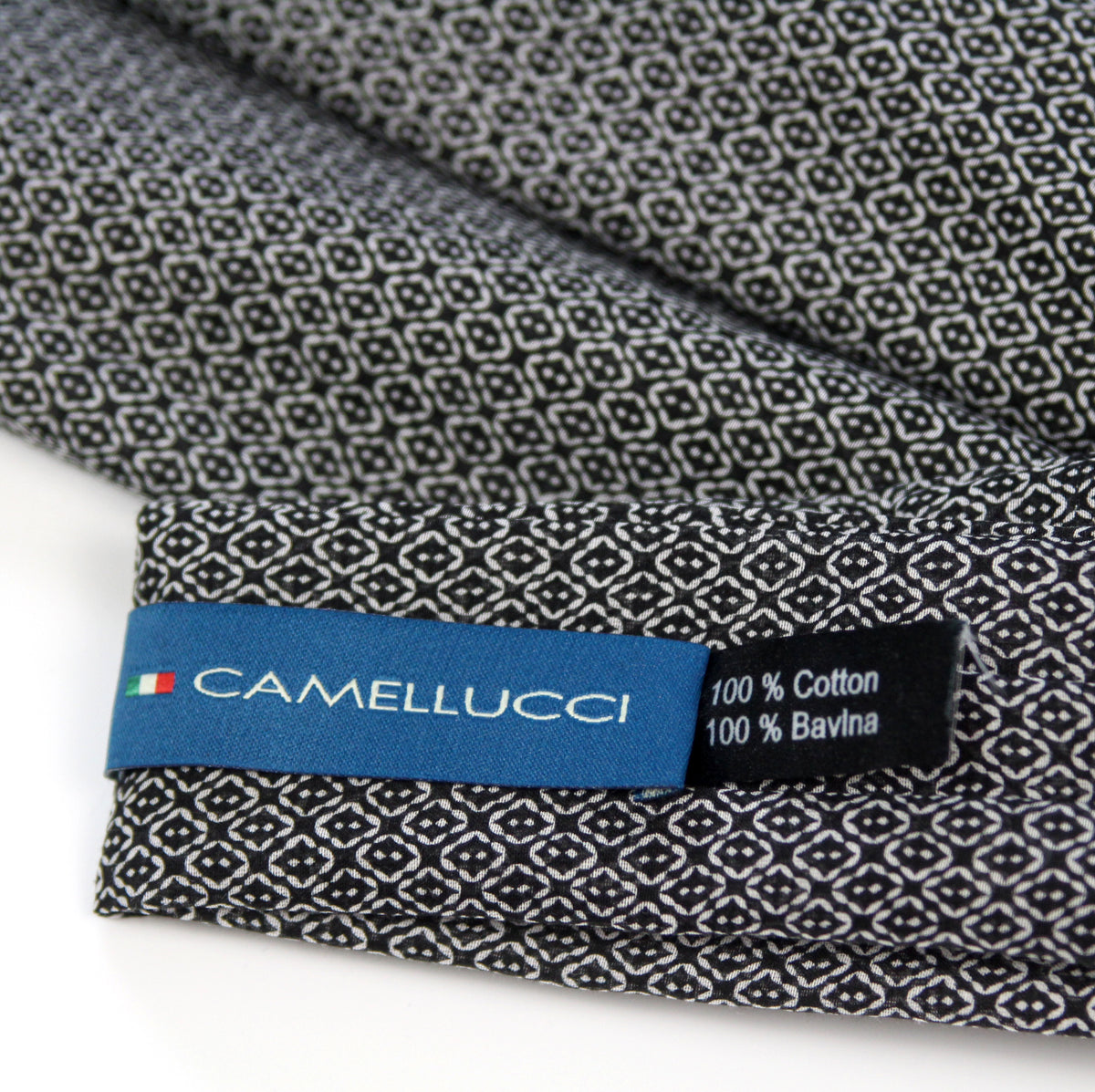 Close-up of a folded Camellucci cotton fabric with a black and white geometric pattern, showing a blue brand label and text reading 100% Cotton and 100% Bavlina.