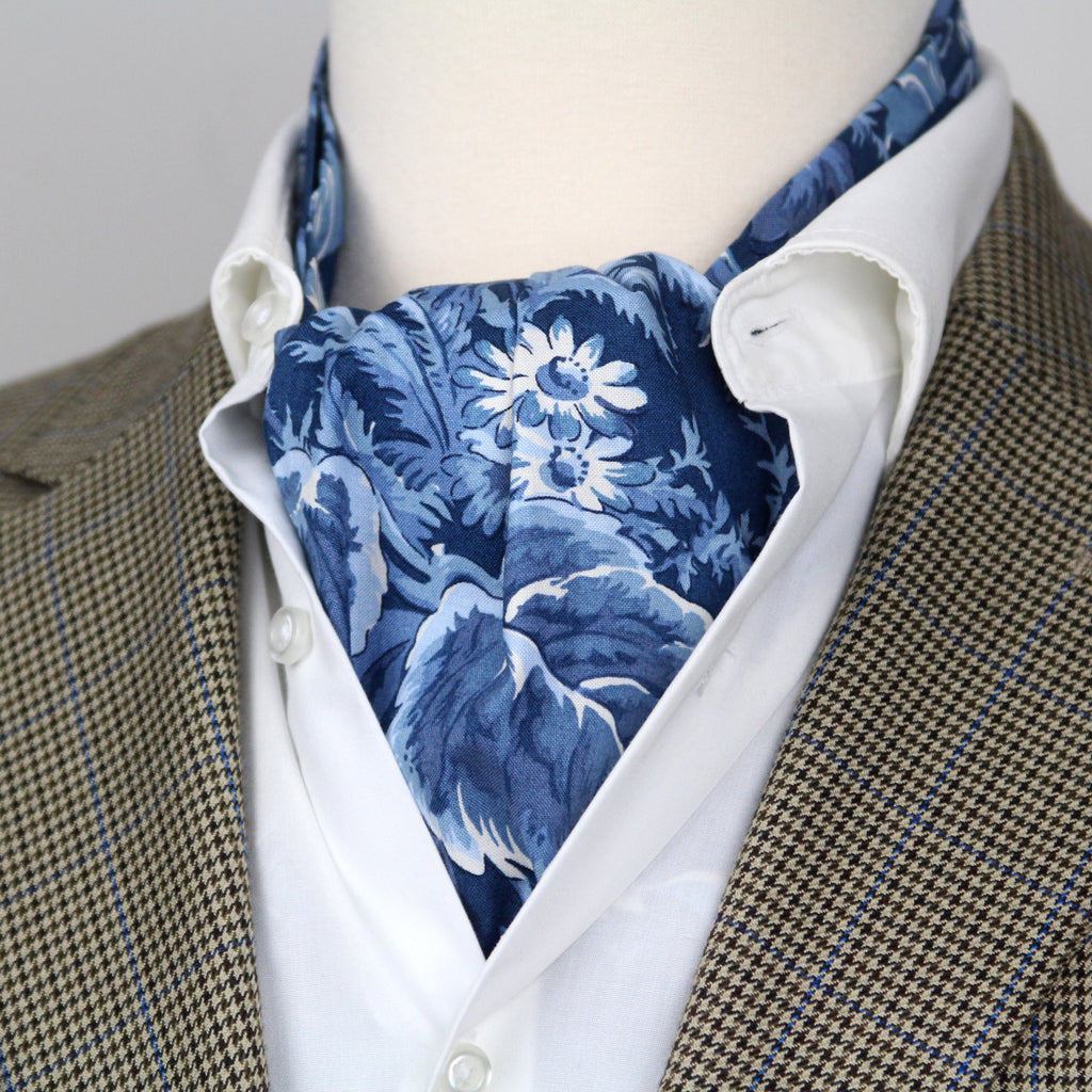 Mannequin wearing a brown suit with a white shirt and blue floral cravat.