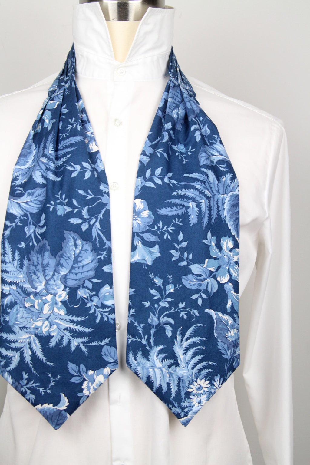 Mannequin wearing a white shirt with a blue floral patterned scarf draped over the shoulders.