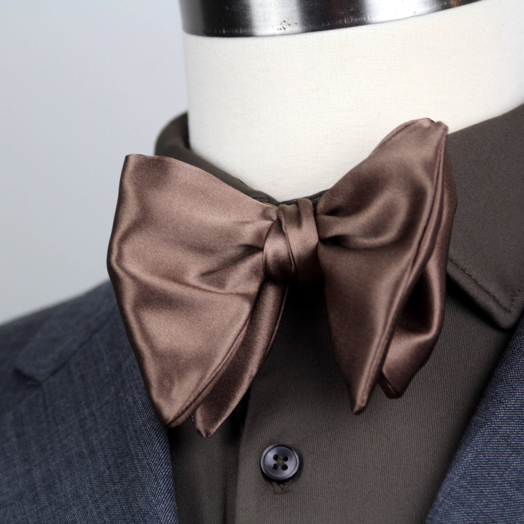 Brown bow tie on a mannequin wearing a suit jacket.