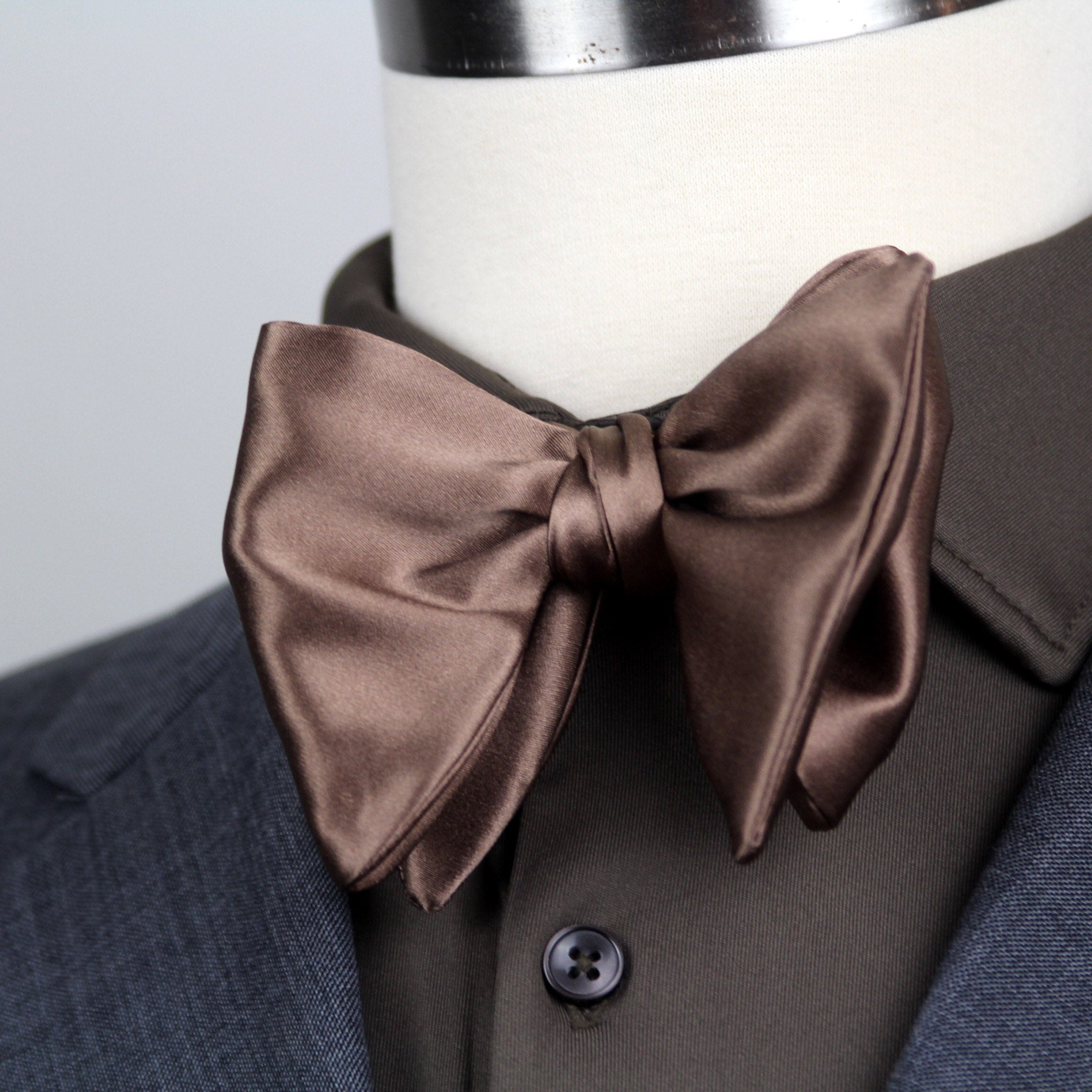 Brown bow tie on a mannequin wearing a suit jacket.