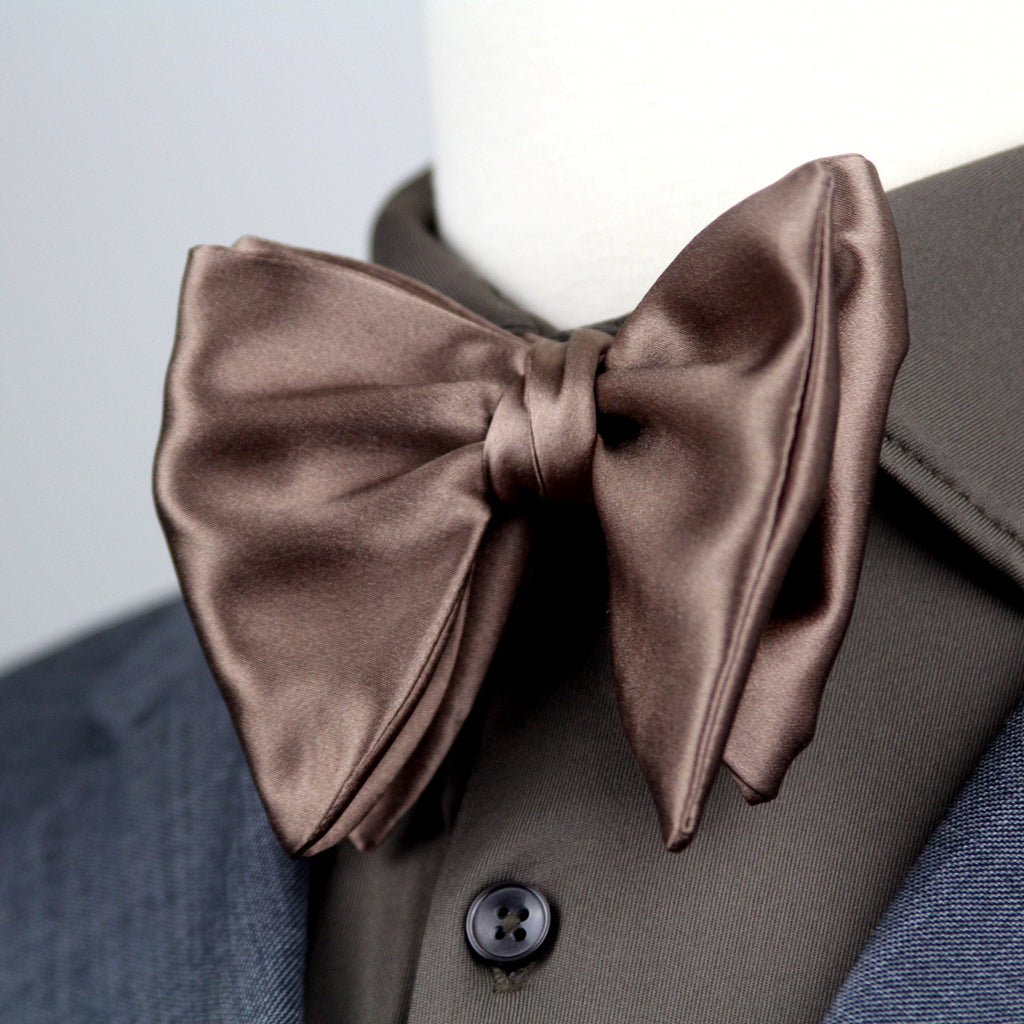 Brown satin bow tie on a mannequin with a gray suit jacket.
