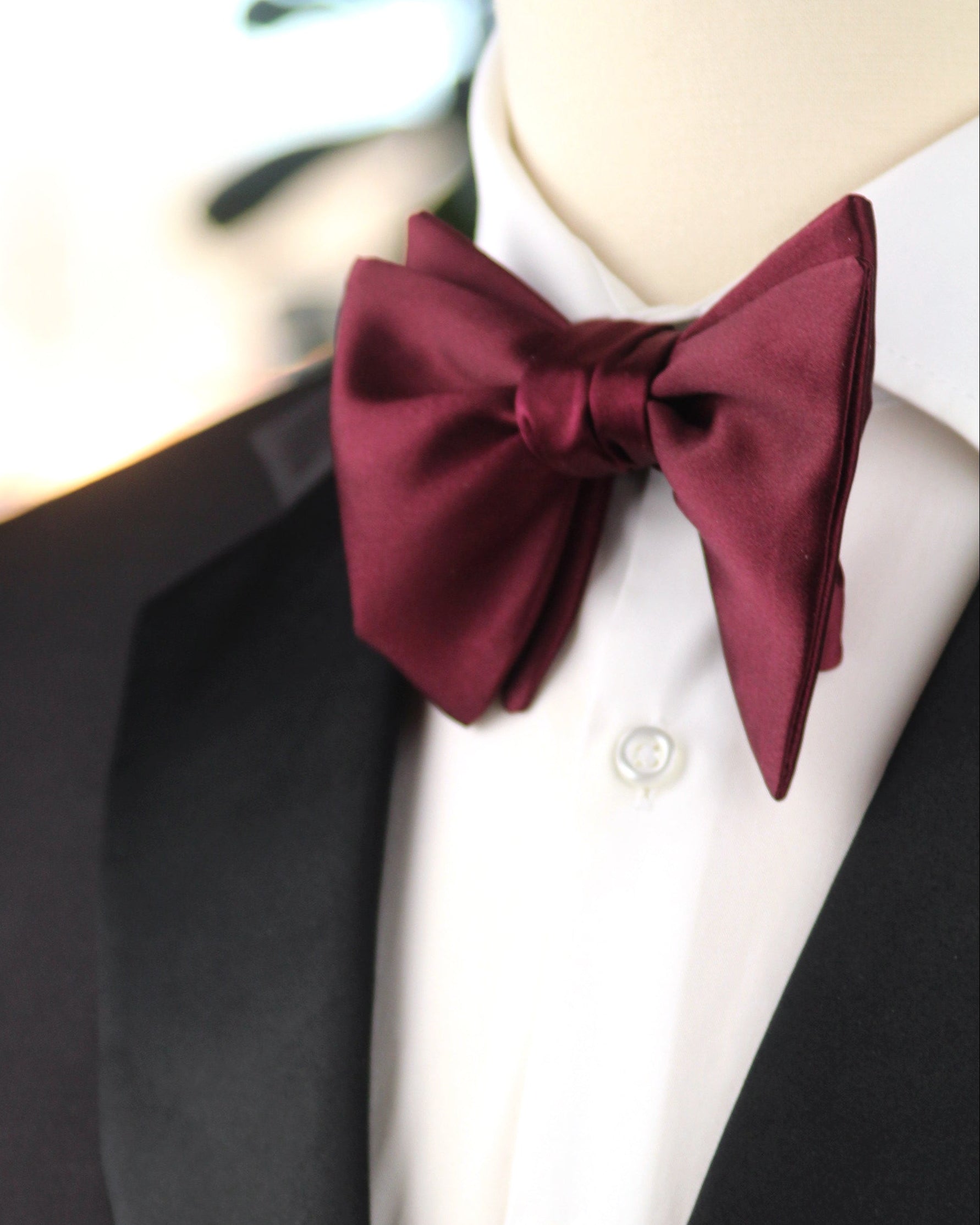 Mannequin wearing a black tuxedo with a white shirt and burgundy bow tie.