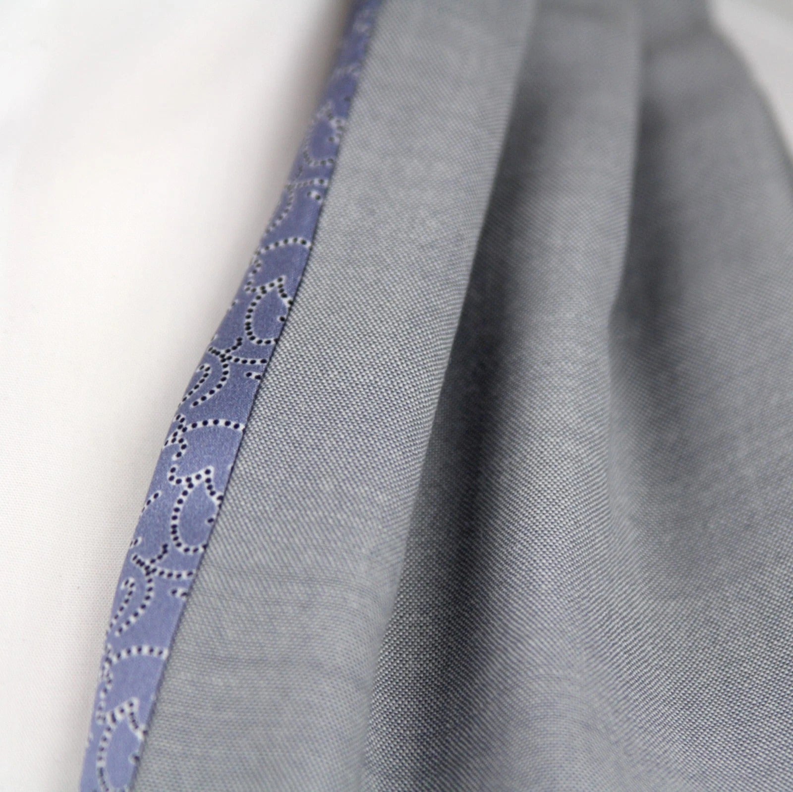 Close-up of gray fabric with a blue trim on a white background