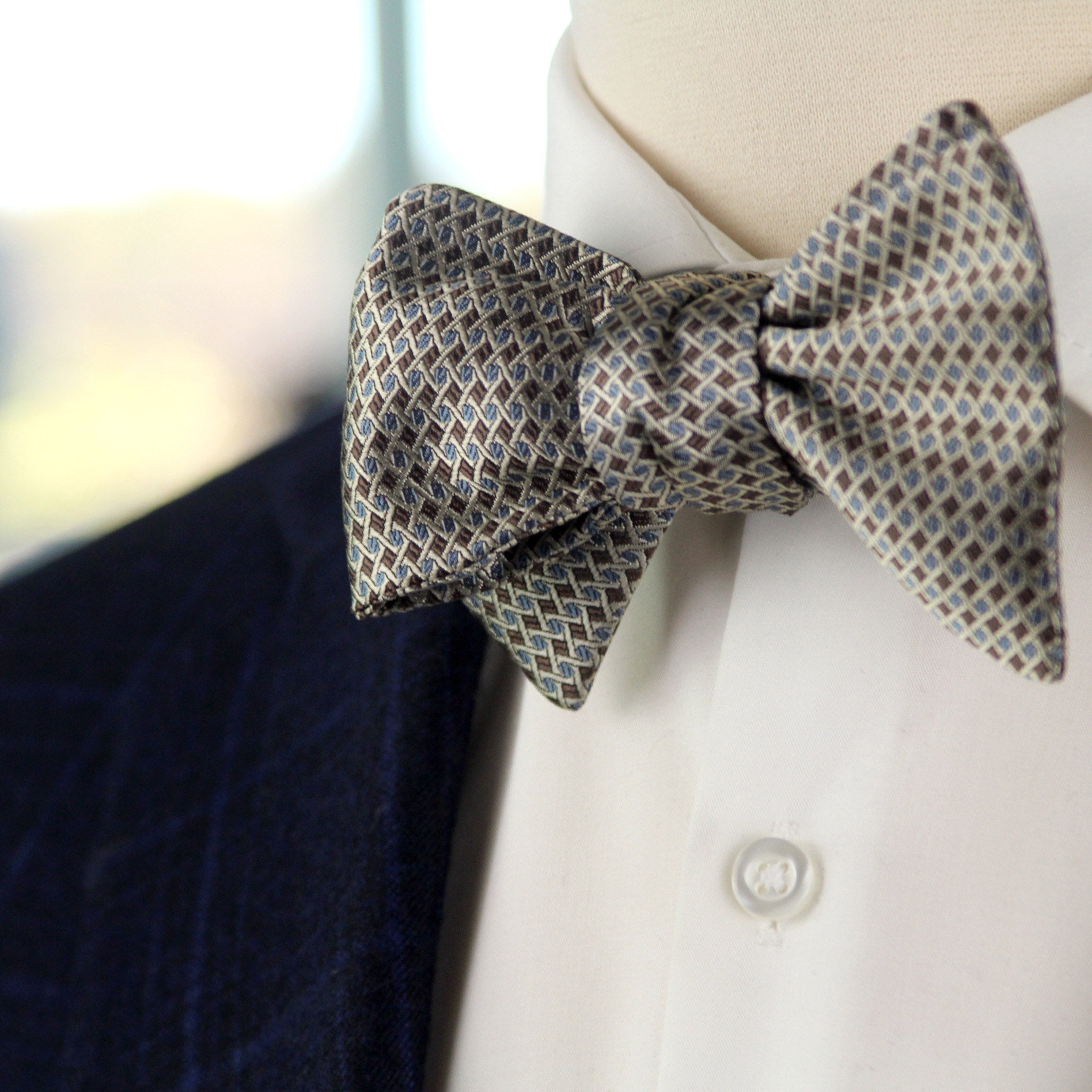 Patterned bow tie on a mannequin wearing a suit jacket and shirt.