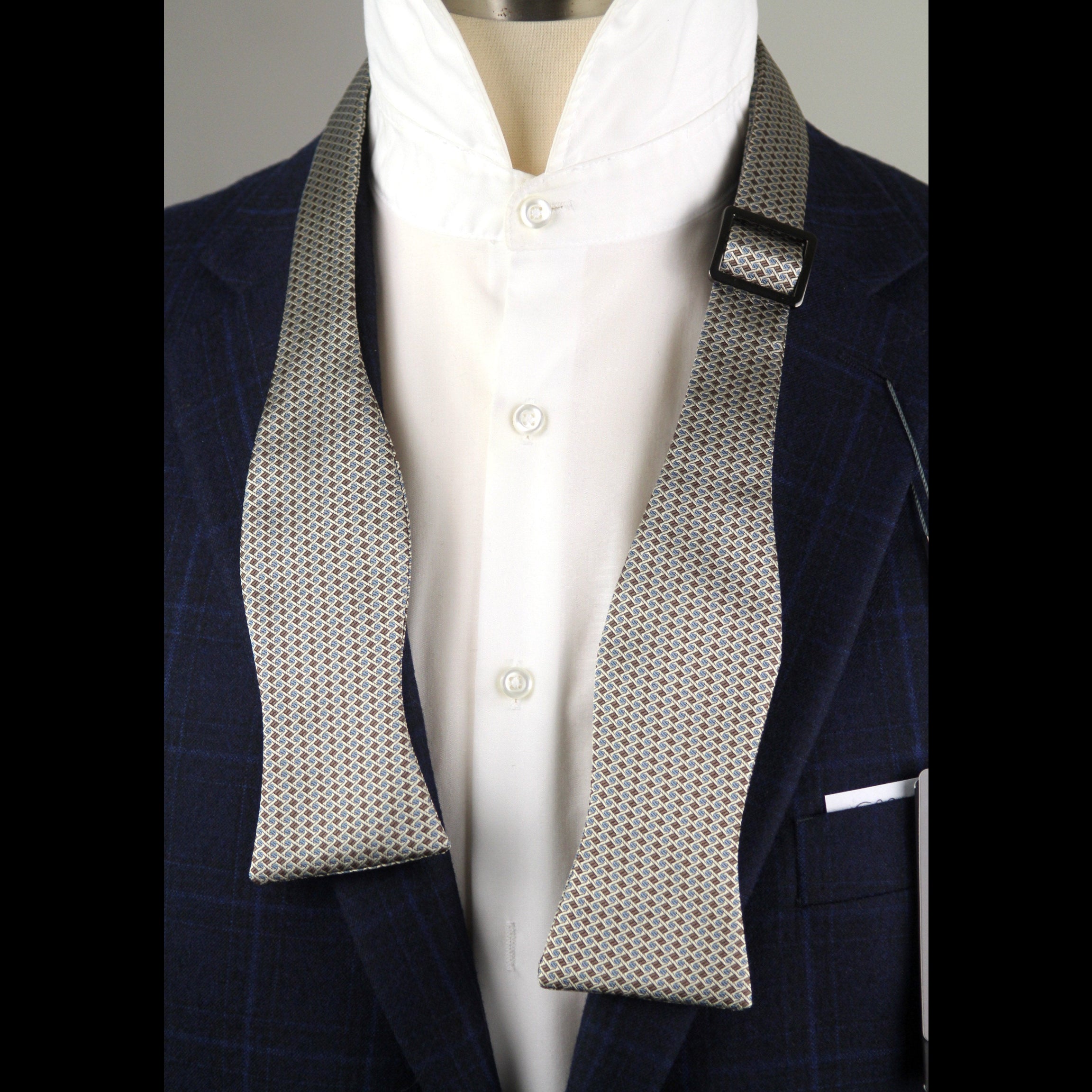 Mannequin wearing a navy blazer with a textured gray tie and white shirt.
