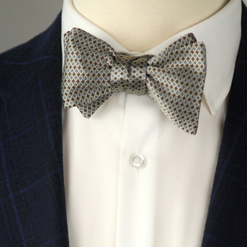 Mannequin wearing a navy blazer, white shirt, and patterned bow tie.