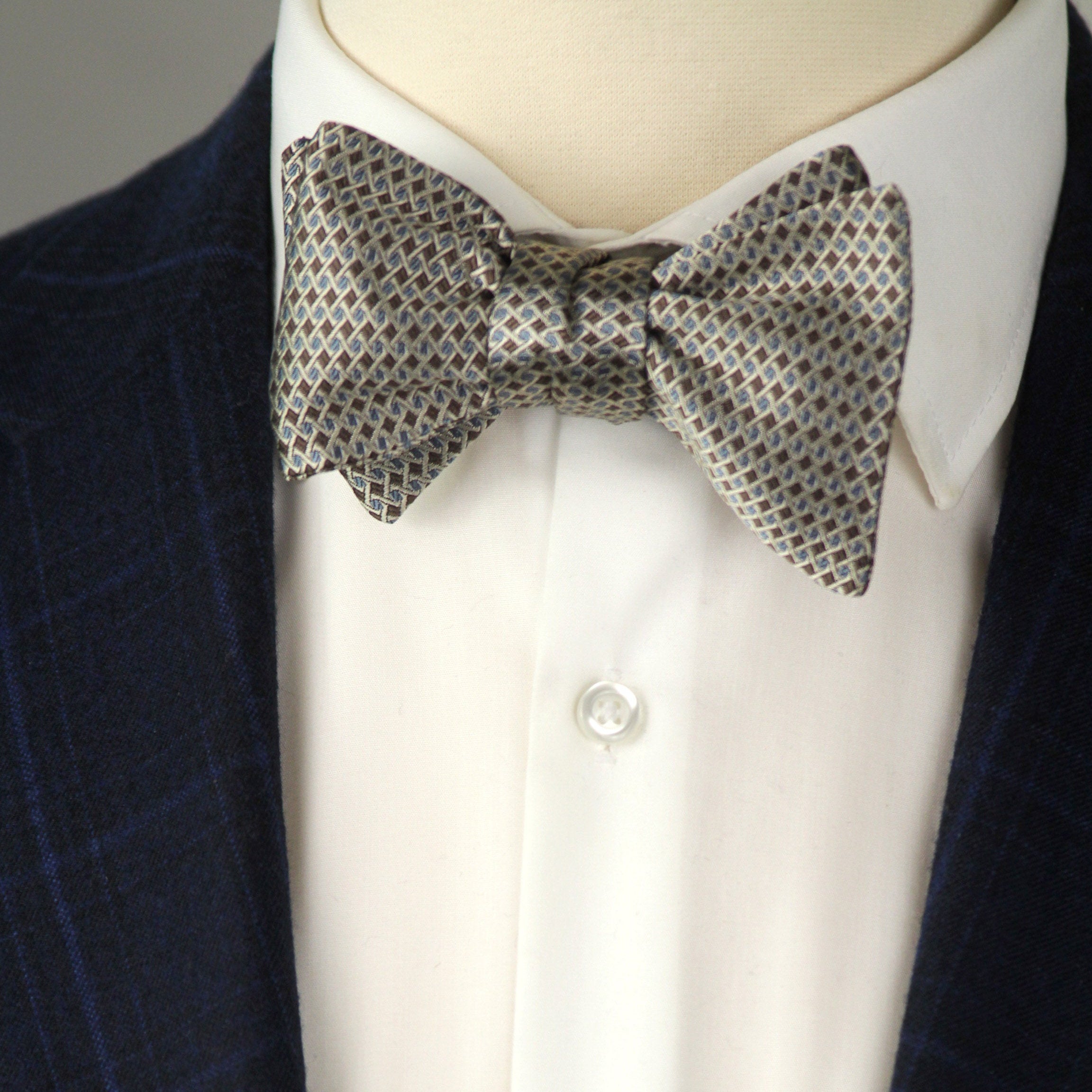 Mannequin wearing a navy blazer, white shirt, and patterned bow tie.
