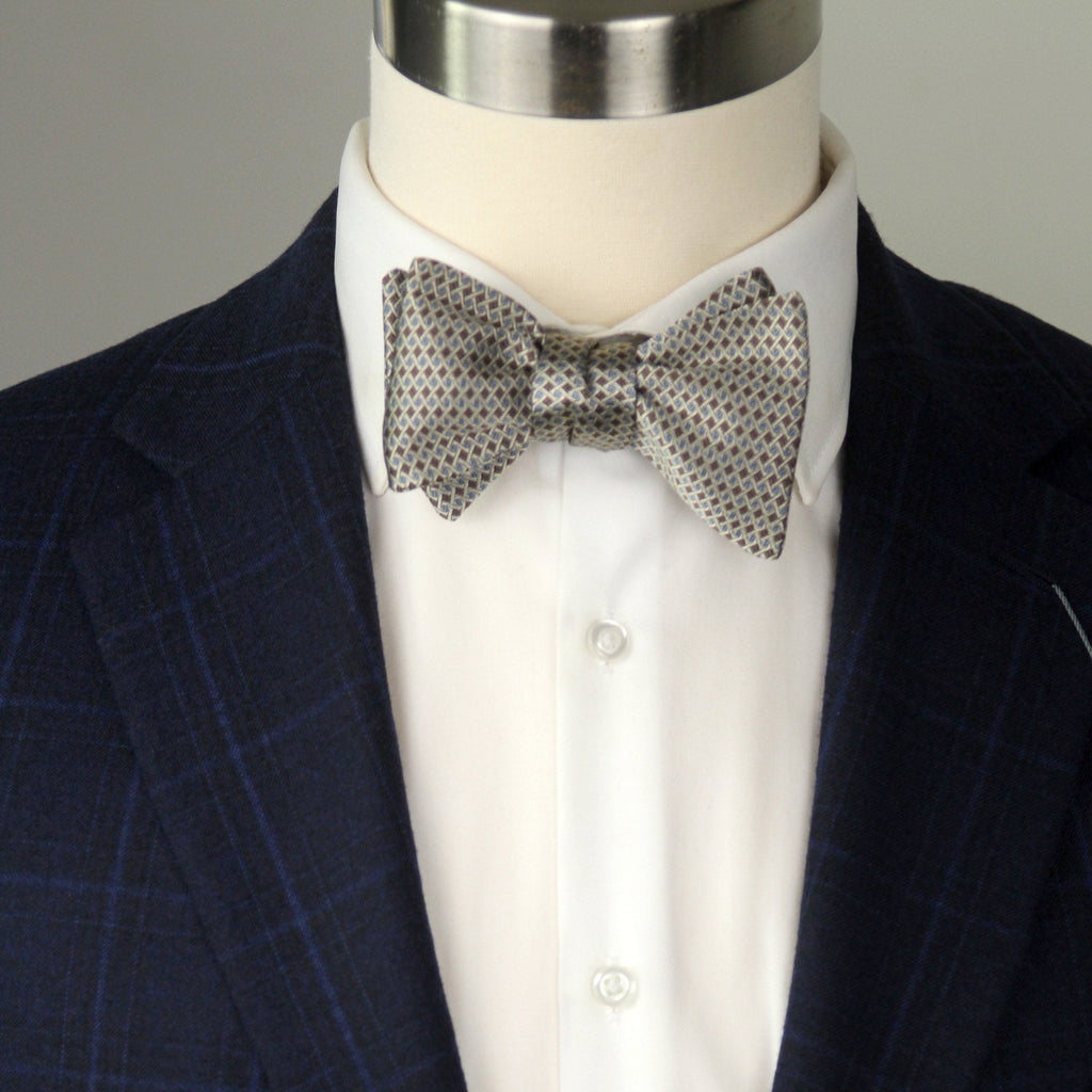 Navy suit jacket with a white shirt and patterned bow tie on a mannequin.
