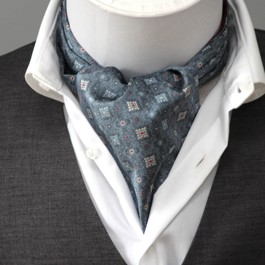 Mannequin wearing a white shirt, gray vest, and patterned cravat against a neutral background