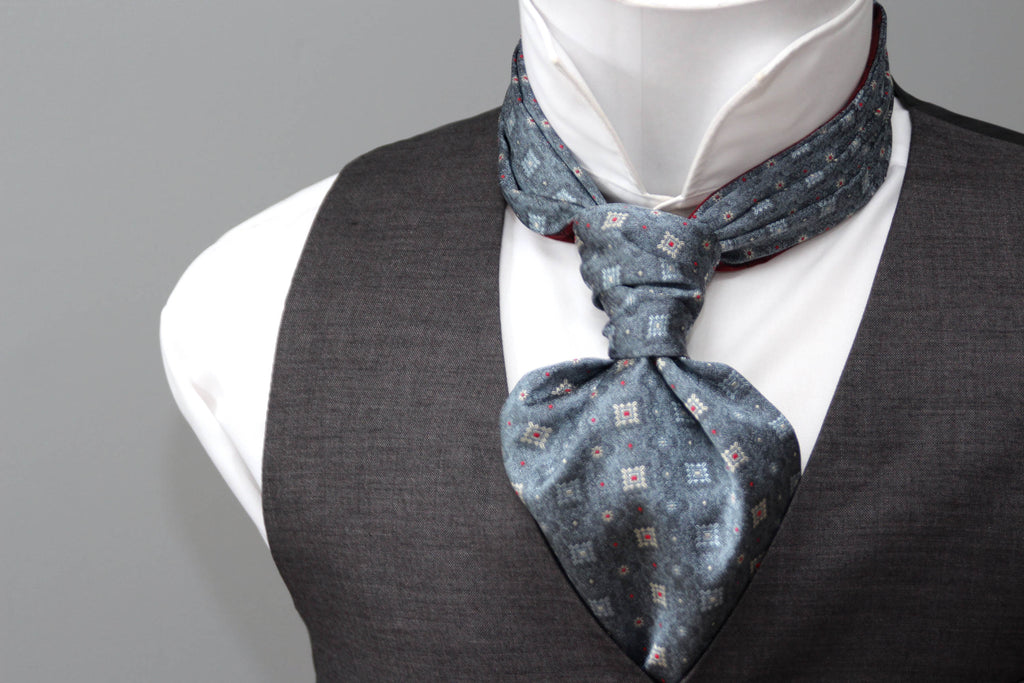 Mannequin wearing a gray vest, white shirt, and patterned cravat against a gray background