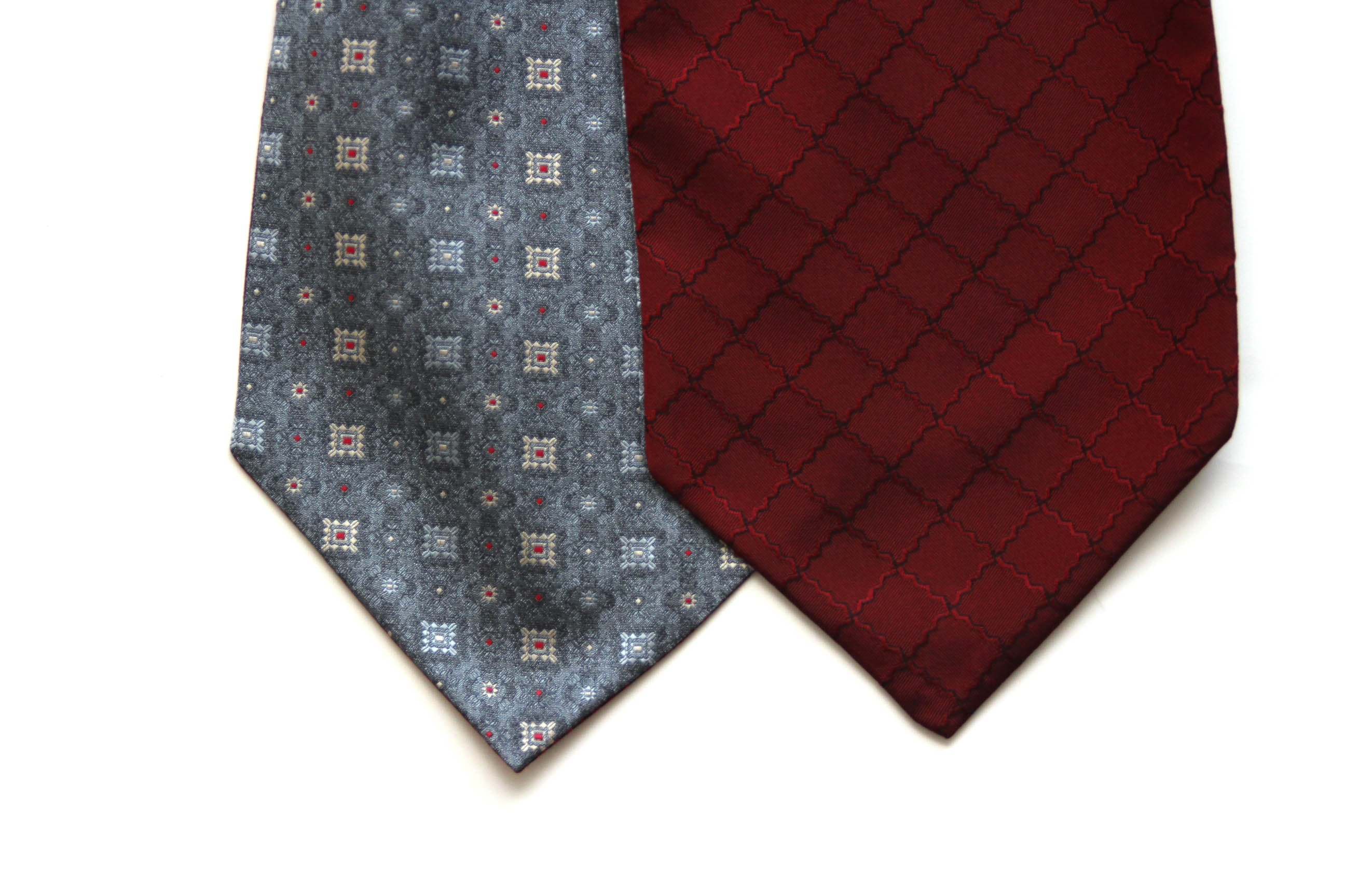 Two patterned ties, one blue with geometric design and one red, on a white background.