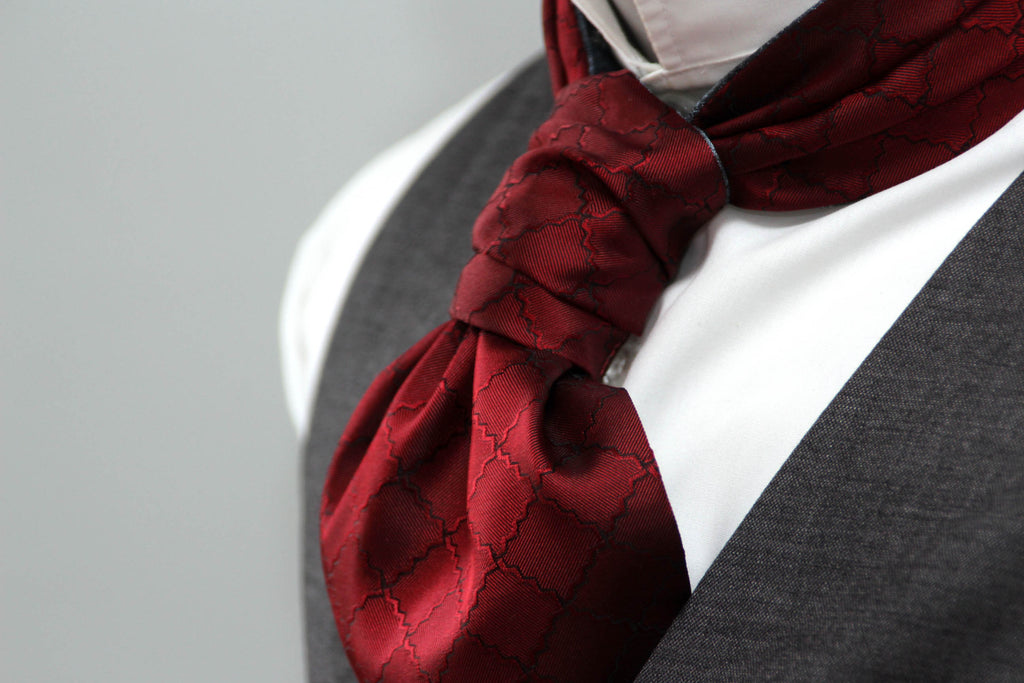 Red patterned scarf around a person's neck with a gray background