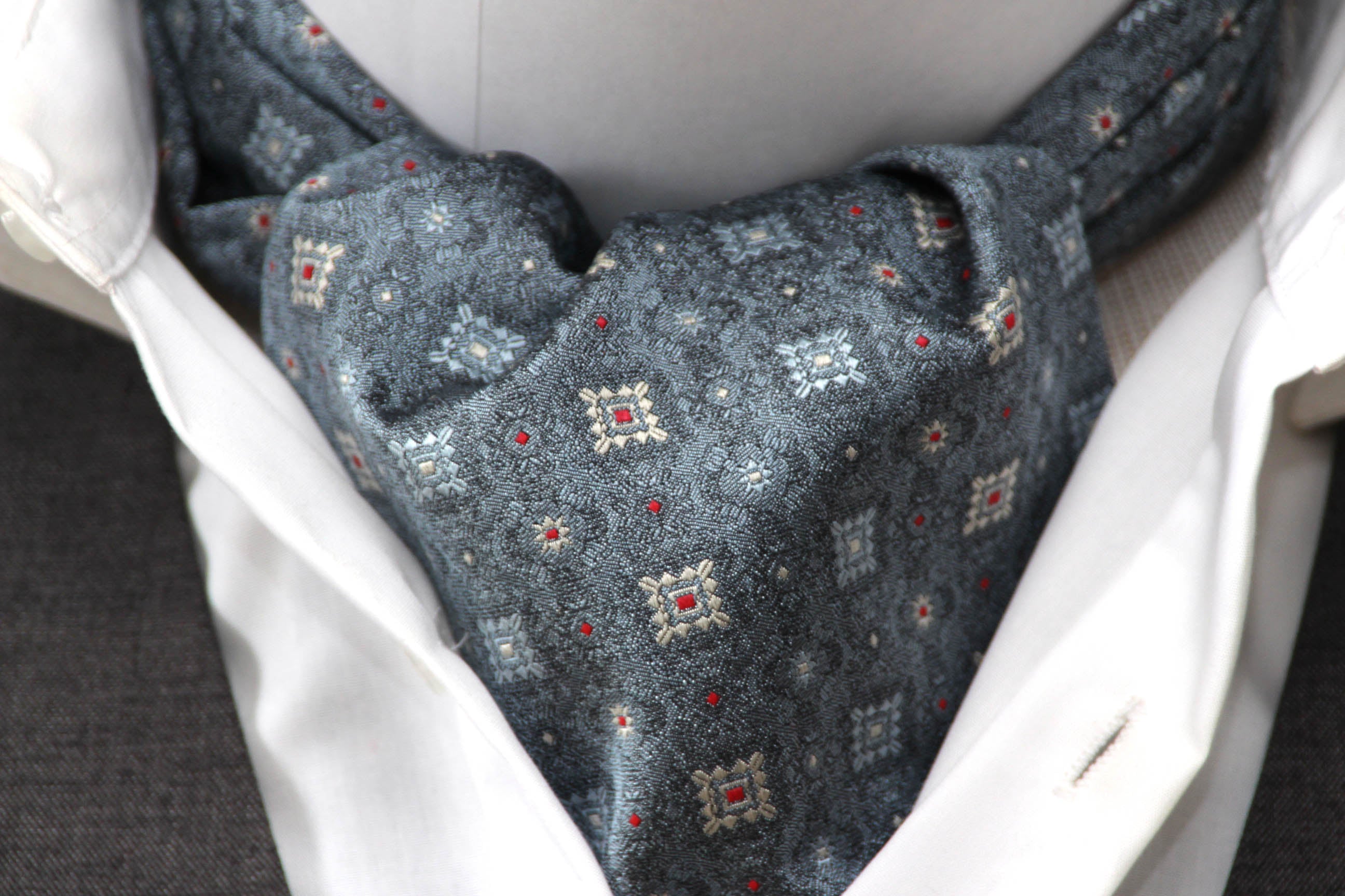 Close-up of a patterned scarf draped over a white garment with a blurred background