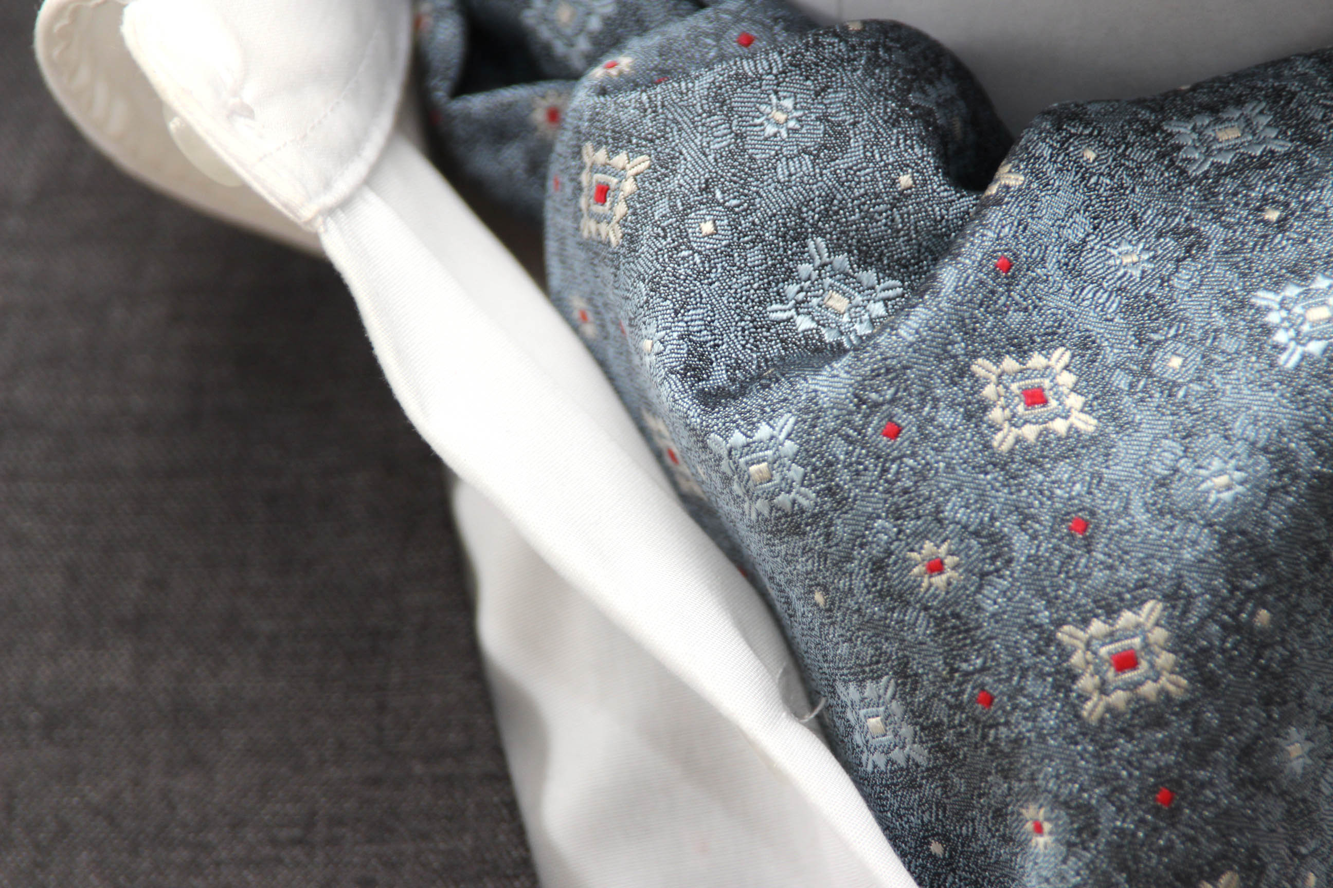 Gray fabric with embroidered patterns on a hanger against a gray background