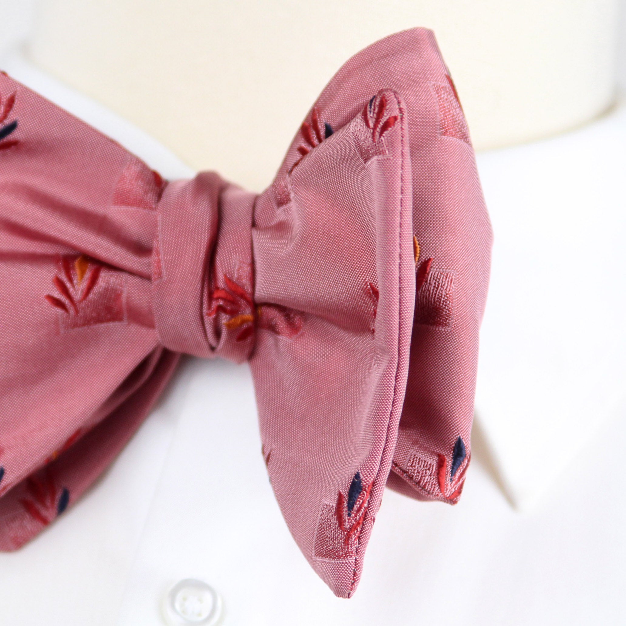 Pink bow tie with floral patterns on a white background