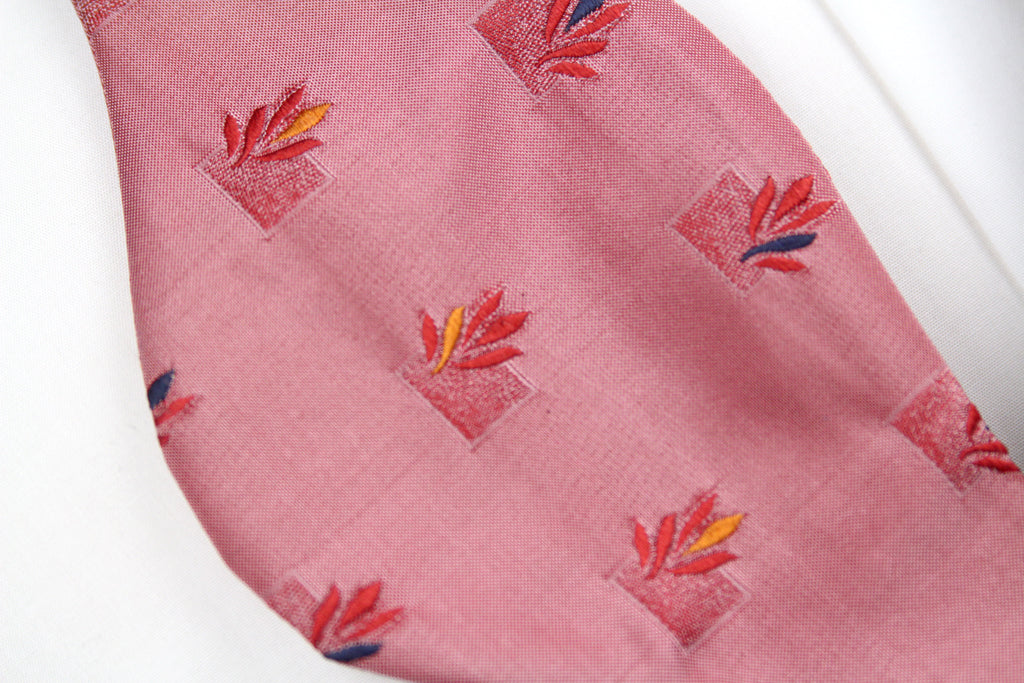 Close-up of a pink fabric with red floral patterns on a white background
