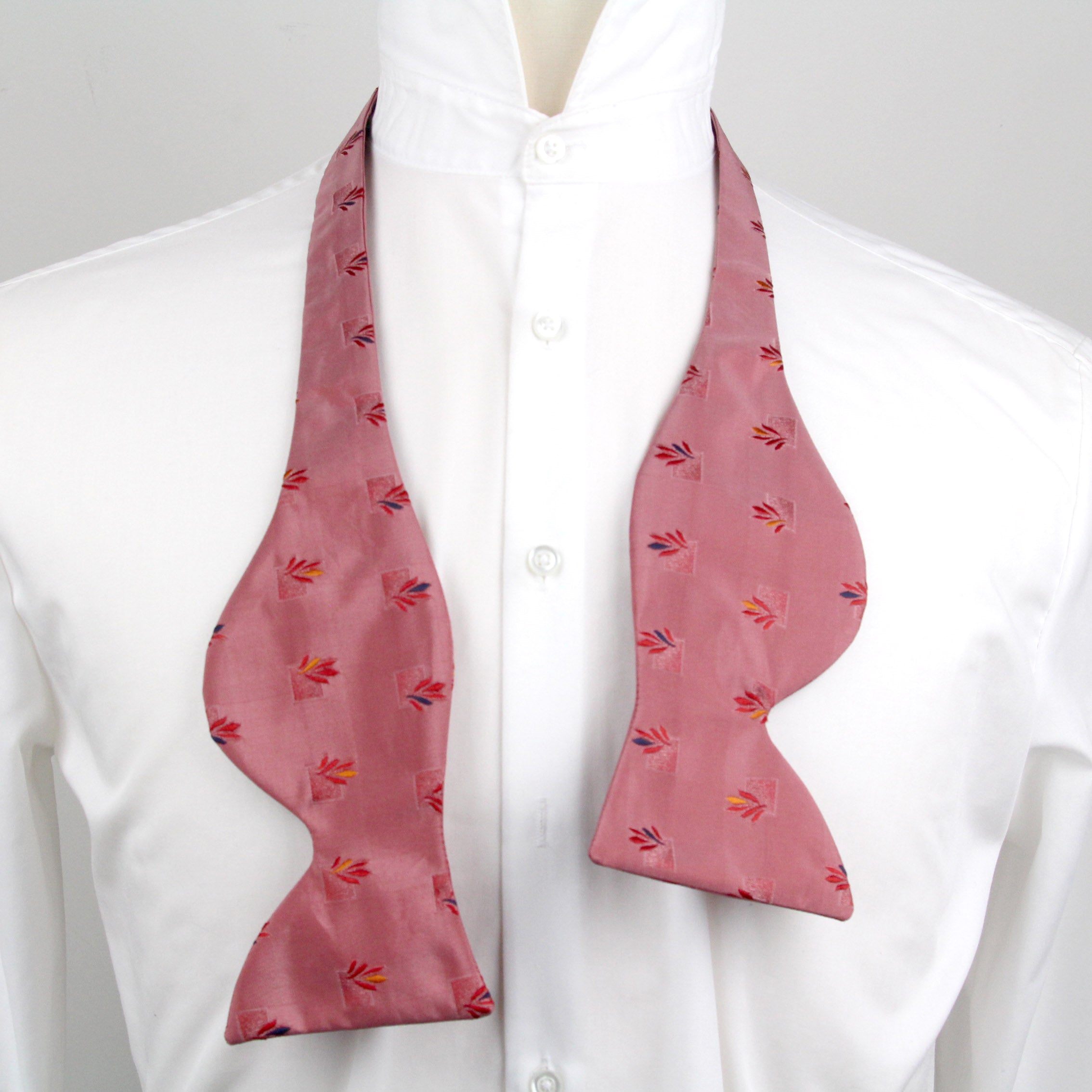 Pink bow tie with a subtle pattern on a white shirt