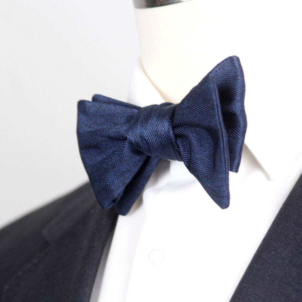 Navy blue bow tie on a white shirt with a black jacket