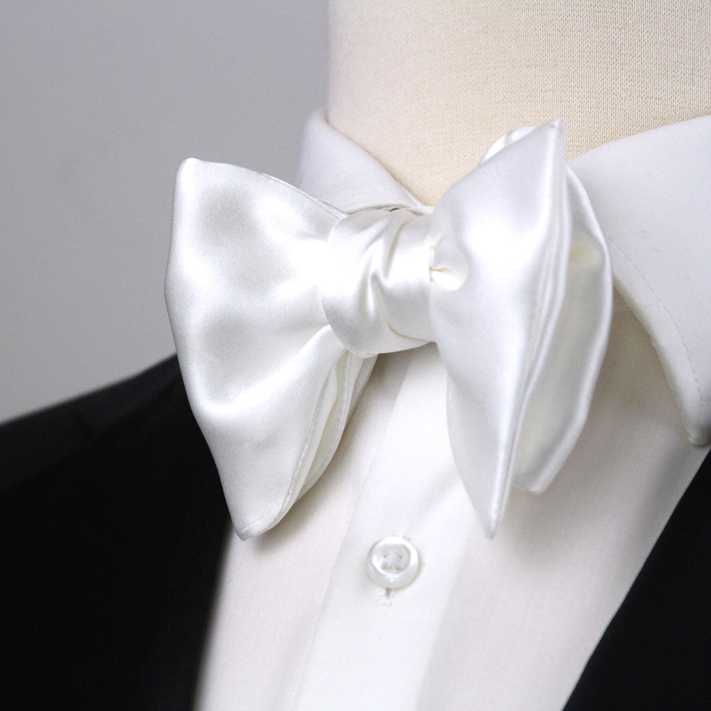 White bow tie on a mannequin with a white shirt and black jacket.
