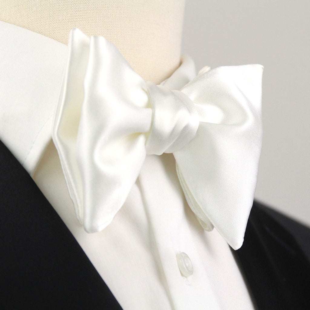 White bow tie on a black and white shirt against a gray background