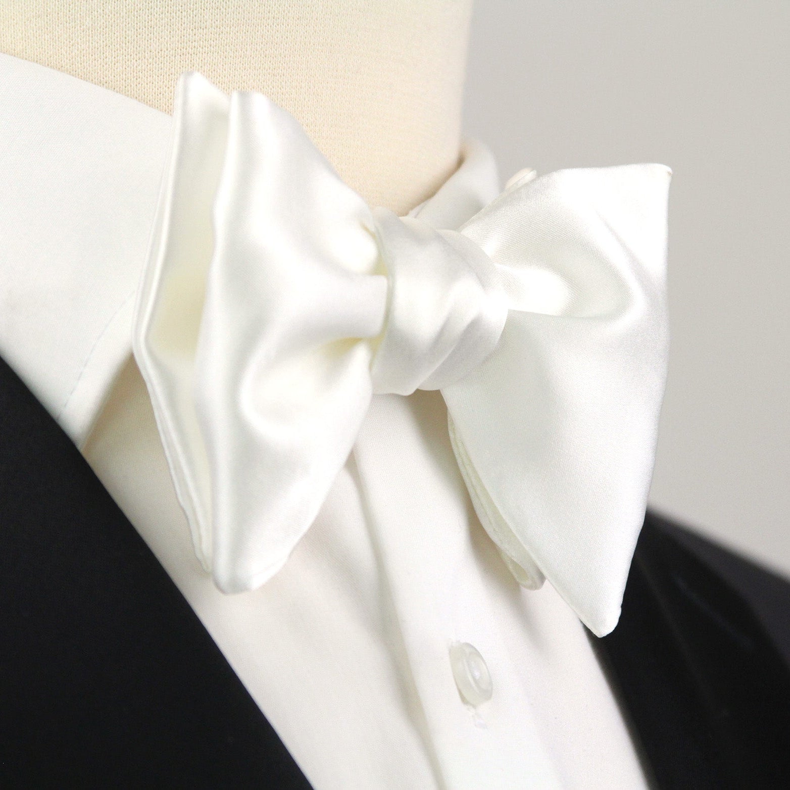White bow tie on a black and white shirt against a gray background