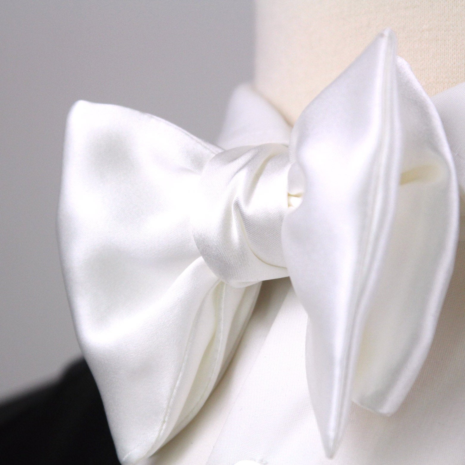 White bow tie on a mannequin head against a neutral background