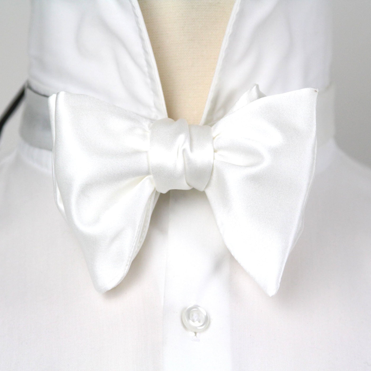 White shirt with a large white bow tie on a plain background