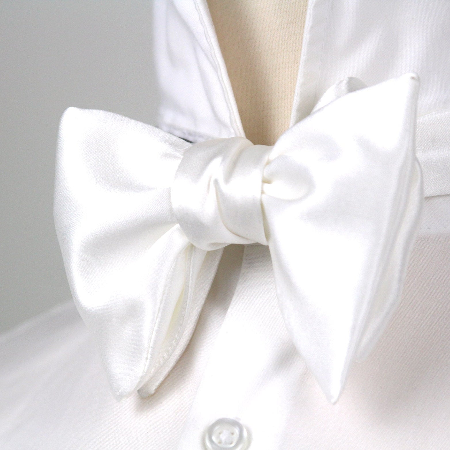 White bow tie on a white shirt against a light gray background