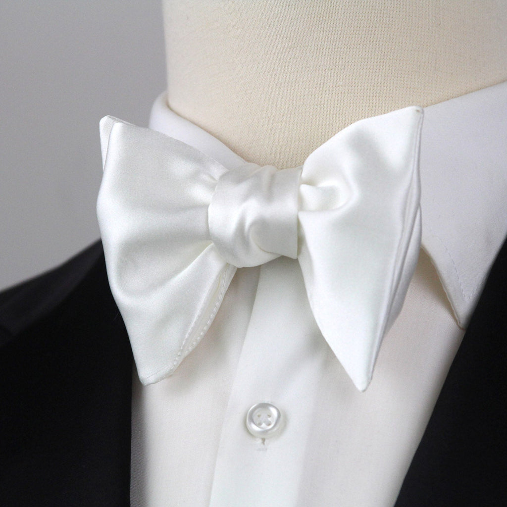 White bow tie on a mannequin wearing a black tuxedo with a white shirt.