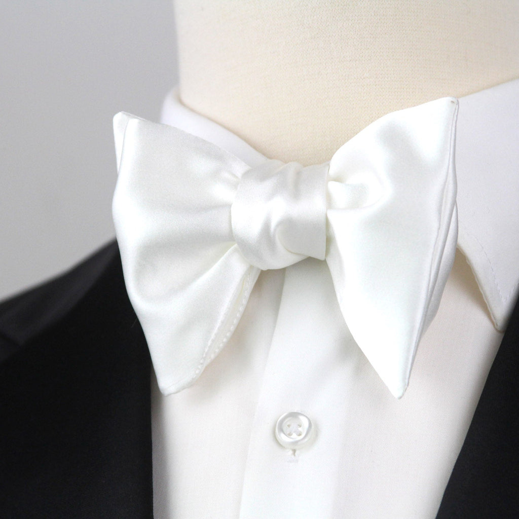 White bow tie on a mannequin with a black tuxedo jacket against a gray background