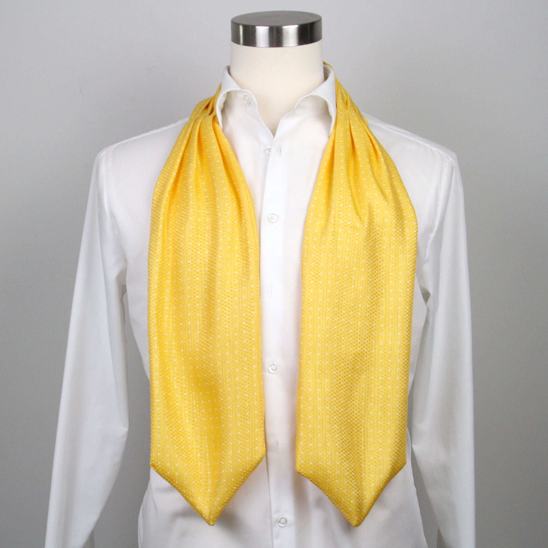 Mannequin wearing a white shirt with a yellow ascot draped over it on a gray background