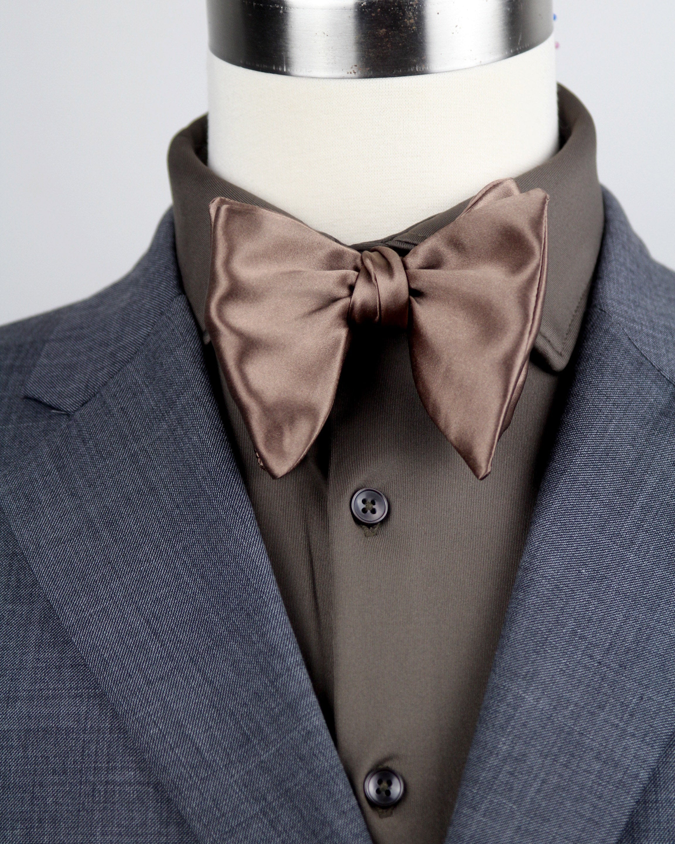 Gray suit with brown bow tie on a mannequin against a gray background