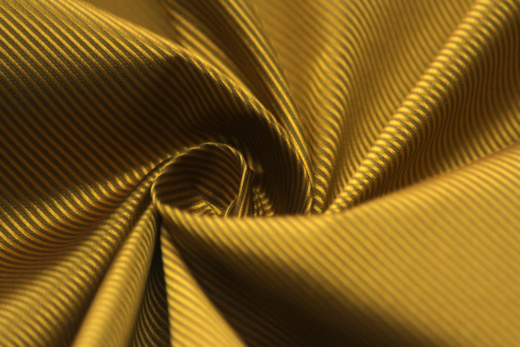 A swatch of gold mustard solid silk fabric with a width of 58 inches, displaying the fabric's texture and color.